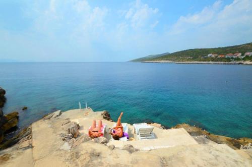 two people laying in the sand on the beach at Apartments Ranko in Zavalatica