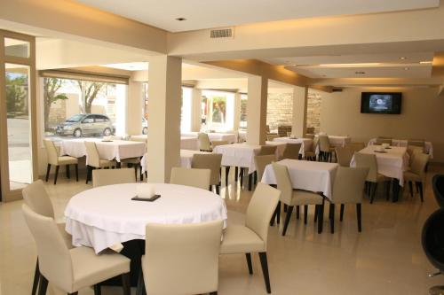 Un comedor con mesas blancas y sillas blancas. en Hotel Casino Hue Melen, en Zapala