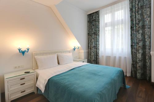 カルロヴィ・ヴァリにあるFerdinandhof Apart-Hotelのベッドルーム1室(青い毛布、窓付)