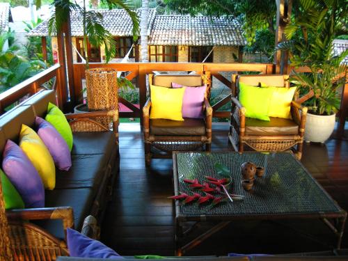 a porch with chairs and a table with colorful pillows at ThalassaGarden Hotel - Pousada in Pipa