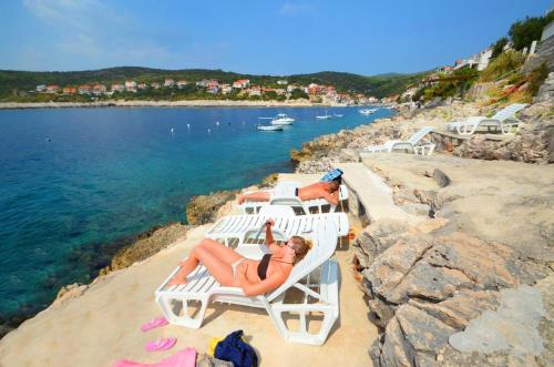 two women laying on lounge chairs on a beach at Apartments Ranko in Zavalatica
