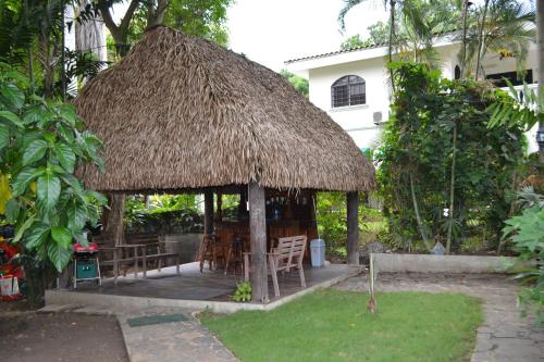 a gazebo with tables and chairs and a straw roof at The Balboa Inn in Panama City