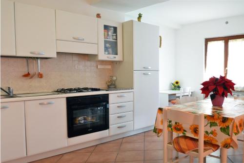 Fossato di VicoにあるAppartamento Bellavistaの白いキャビネットとキッチンテーブル付きのキッチン