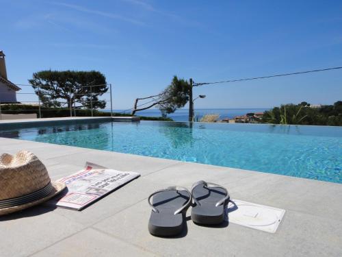 a pair of flip flops and a hat next to a swimming pool at Home Cassis - Maison Méditerranée - Piscine chauffée à 30c in Cassis