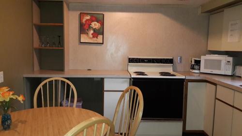 a kitchen with a black and white stove and a table at Pinebrook Motel in Lake George