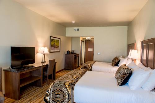 a hotel room with two beds and a desk with a television at Cedar Creek Lodge & Conference Center in Columbia Falls