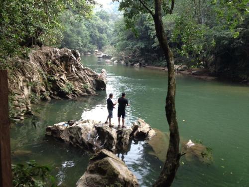 two people standing on a rock in a river at Biohotel Rio Claro in Doradal
