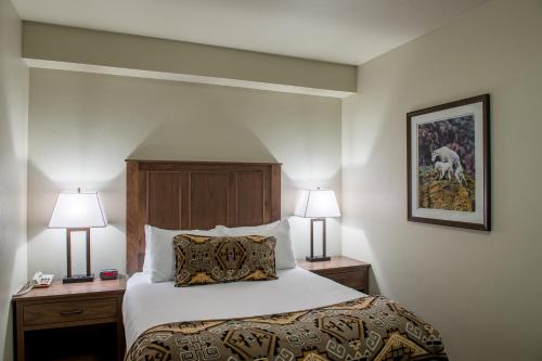 a hotel room with a bed with two night stands and two lamps at Cedar Creek Lodge & Conference Center in Columbia Falls