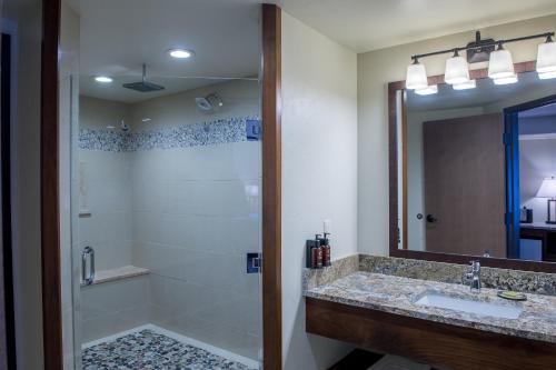 a bathroom with a shower and a sink and a mirror at Cedar Creek Lodge & Conference Center in Columbia Falls