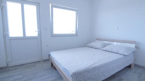 a white bedroom with a bed and two windows at Apartments Domani in Vir