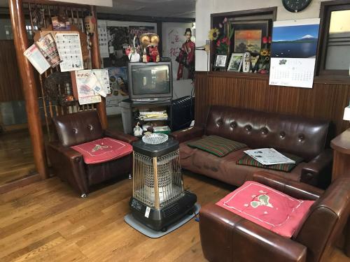 a living room with leather furniture and a tv at Niko Ryokan in Aizuwakamatsu
