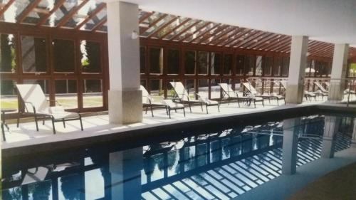 a swimming pool with chairs and a building at Flat Vista Azul in Pedra Azul