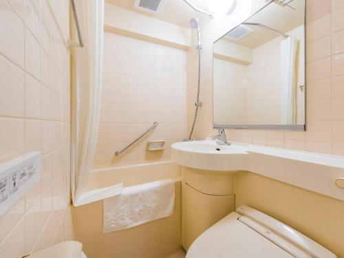 een badkamer met een toilet, een wastafel en een spiegel bij HOTEL MYSTAYS Sapporo Nakajima Park Annex in Sapporo