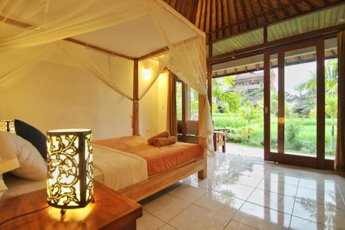 ein Schlafzimmer mit einem Himmelbett in einem Zimmer mit Fenstern in der Unterkunft Sari Bungalow in Ubud