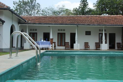 a swimming pool in front of a house at Paradise Forest Garden in Matale