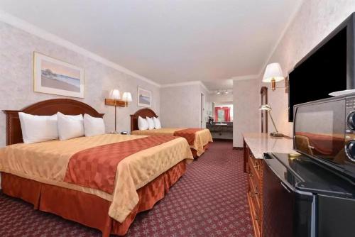 Habitación de hotel con 2 camas y TV de pantalla plana. en Americas Best Value Inn & Suites - Fontana en Fontana