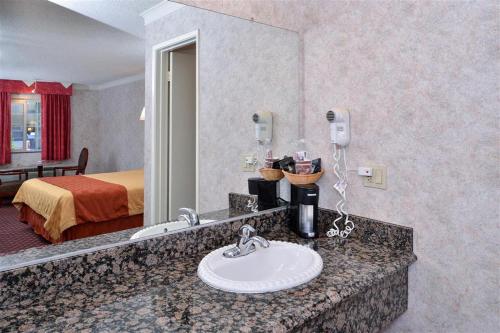 a hotel room with a bathroom with a sink and a bed at Americas Best Value Inn & Suites - Fontana in Fontana