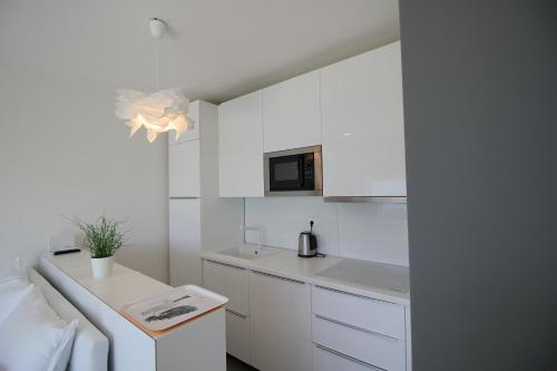 een witte keuken met witte kasten en een aanrecht bij Apartments Sky in Rijeka