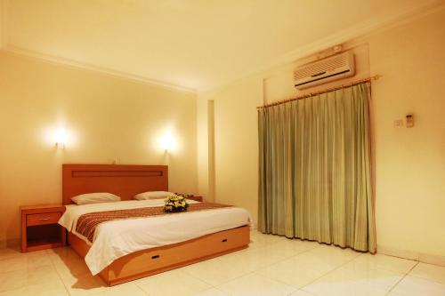 um quarto com uma cama e uma janela com flores em Syariah Arini Hotel em Surakarta