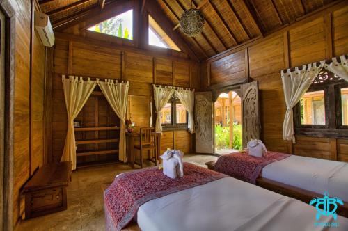 two beds in a room with wooden walls and windows at Benthos Bali Dive Resort in Candidasa