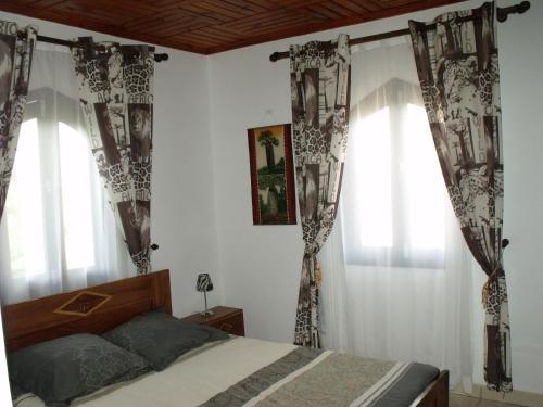 a bedroom with a bed and two windows at Iarimbato Hotel in Antananarivo
