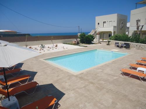 a swimming pool with chairs and the ocean in the background at Almyra Apartments & Suites in Sfakaki