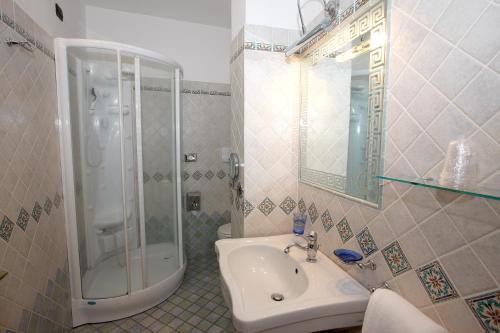 uma casa de banho com um chuveiro, um lavatório e um espelho. em Hotel Palazzo Krataiis em Scilla