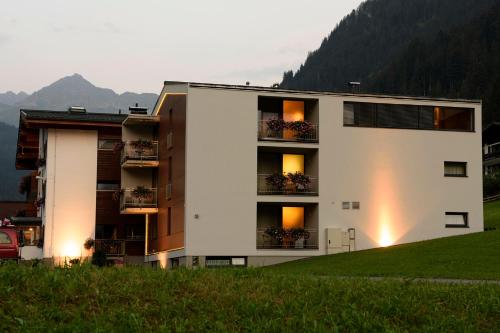 a building on a hill with mountains in the background at Hotel Silbertal in Silbertal