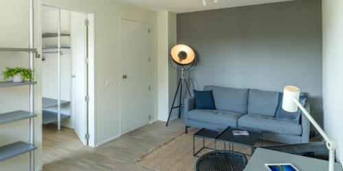 a living room with a blue couch and a spotlight at B&B Antares in Bruges