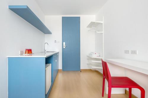 een keuken met een rode stoel en een blauwe deur bij 128 room and massage in Bangkok