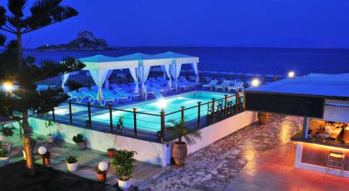 a swimming pool with chairs and the ocean at night at Sacallis Inn Beach Hotel in Kefalos