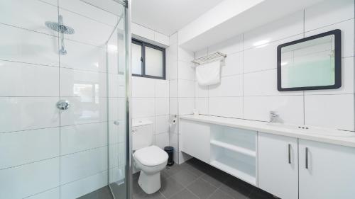 La salle de bains blanche est pourvue de toilettes et d'un lavabo. dans l'établissement Batavia Apartments, à Perth