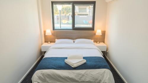 a small bedroom with a bed and two lamps at Batavia Apartments in Perth