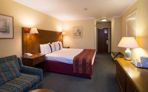 um quarto de hotel com uma cama e uma cadeira em Citrus Hotel Coventry South by Compass Hospitality em Coventry