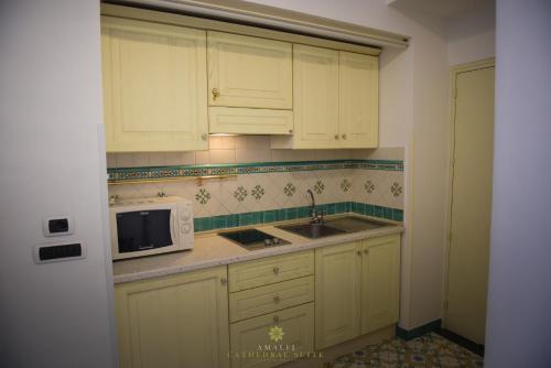 a kitchen with white cabinets and a microwave at Amalfi Cathedral Suite in Amalfi