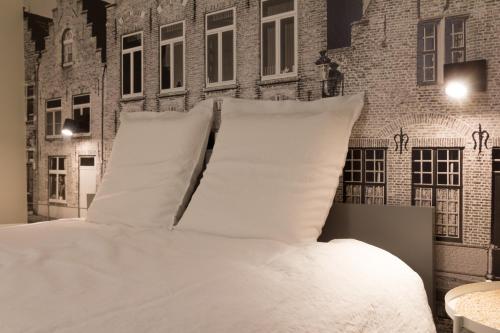 a bed with white sheets and pillows in a room at B&B Antares in Bruges