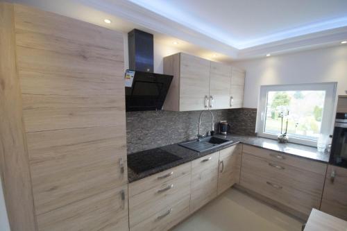 a kitchen with wooden cabinets and a sink and a window at Pension / Zimmervermietung Wasbek in Wasbek
