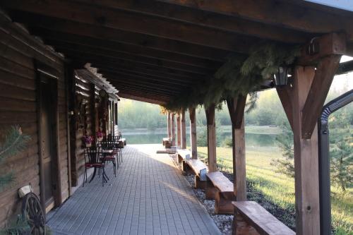 a porch of a log cabin with benches and tables at Viesu māja Forrest in Dzimtmisa