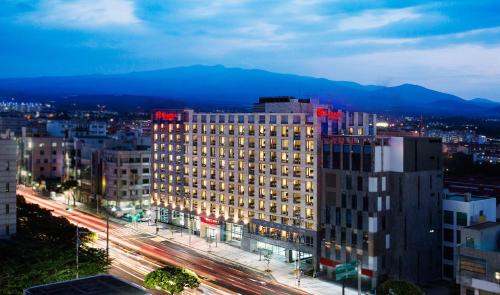 a tall building with red lights on top of it at Ramada by Wyndham Jeju City Hall in Jeju