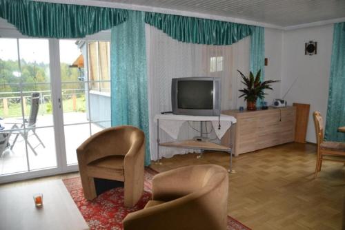 ein Wohnzimmer mit einem Flachbild-TV und Stühlen in der Unterkunft Erlebnispension Zum Wanderer Sepp in Arnbruck
