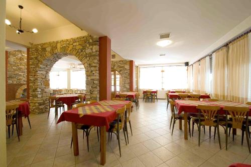 a restaurant with tables and chairs and a stone wall at Lydia Hotel in Krinídhes