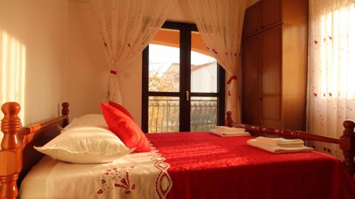 a bed with red and white pillows and a window at Apartments Ivanka in Trogir