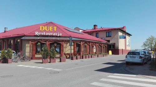 a car parked in front of a restaurant on a street at Hotel Duet in Człuchów