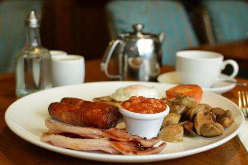 a plate of food with sausage and mushrooms on a table at Rooms At Rue in Omagh