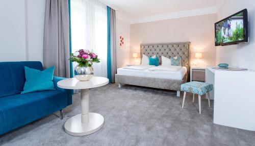 a hotel room with a bed and a blue couch at Villa Christina in Pörtschach am Wörthersee