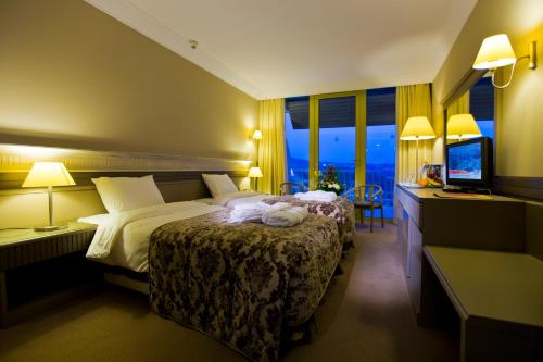 クシャダスにあるFantasia Deluxe Hotelのベッドとテレビがあるホテルの部屋