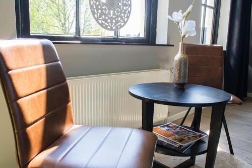 a table and a chair next to a table with a vase at Het Wapen van Rhoon in Rhoon