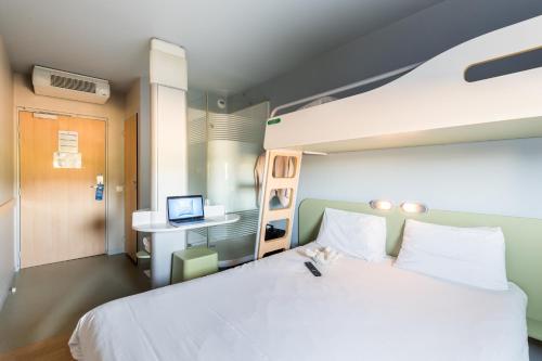 a bedroom with a large white bed and a desk at ibis budget Amberieu en Bugey/Chateau Gaillard A42 in Château-Gaillard