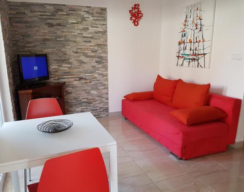a living room with a red couch and a table at Apartments Antonio in Cavtat