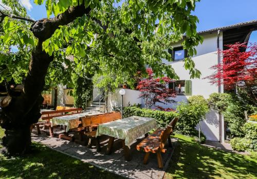 a picnic table and benches under a tree in a yard at Garni Meinrad in Ora/Auer